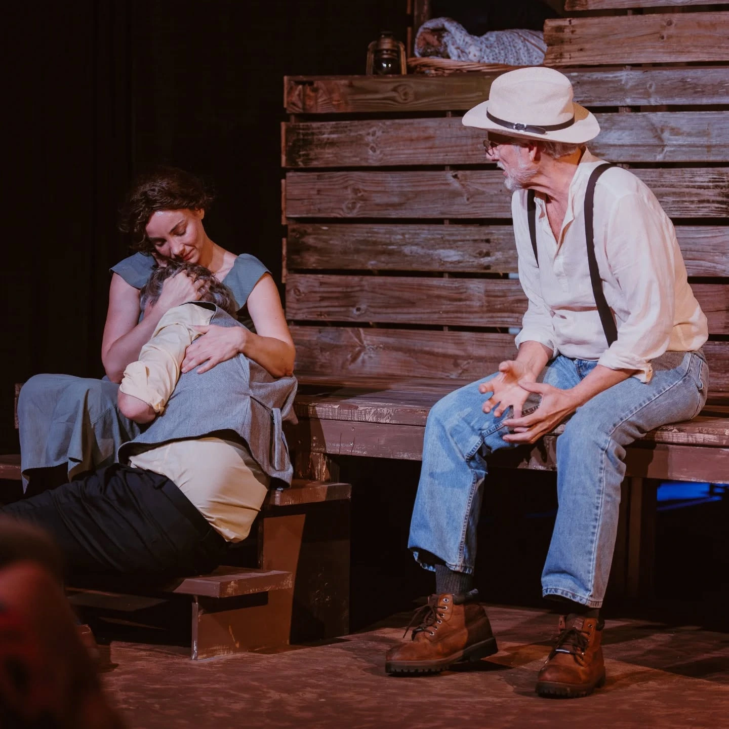 Josie cradles Tyrone’s head in her lap as Phil sits nearby on the farmhouse steps in 'A Moon for the Misbegotten' at ABET.