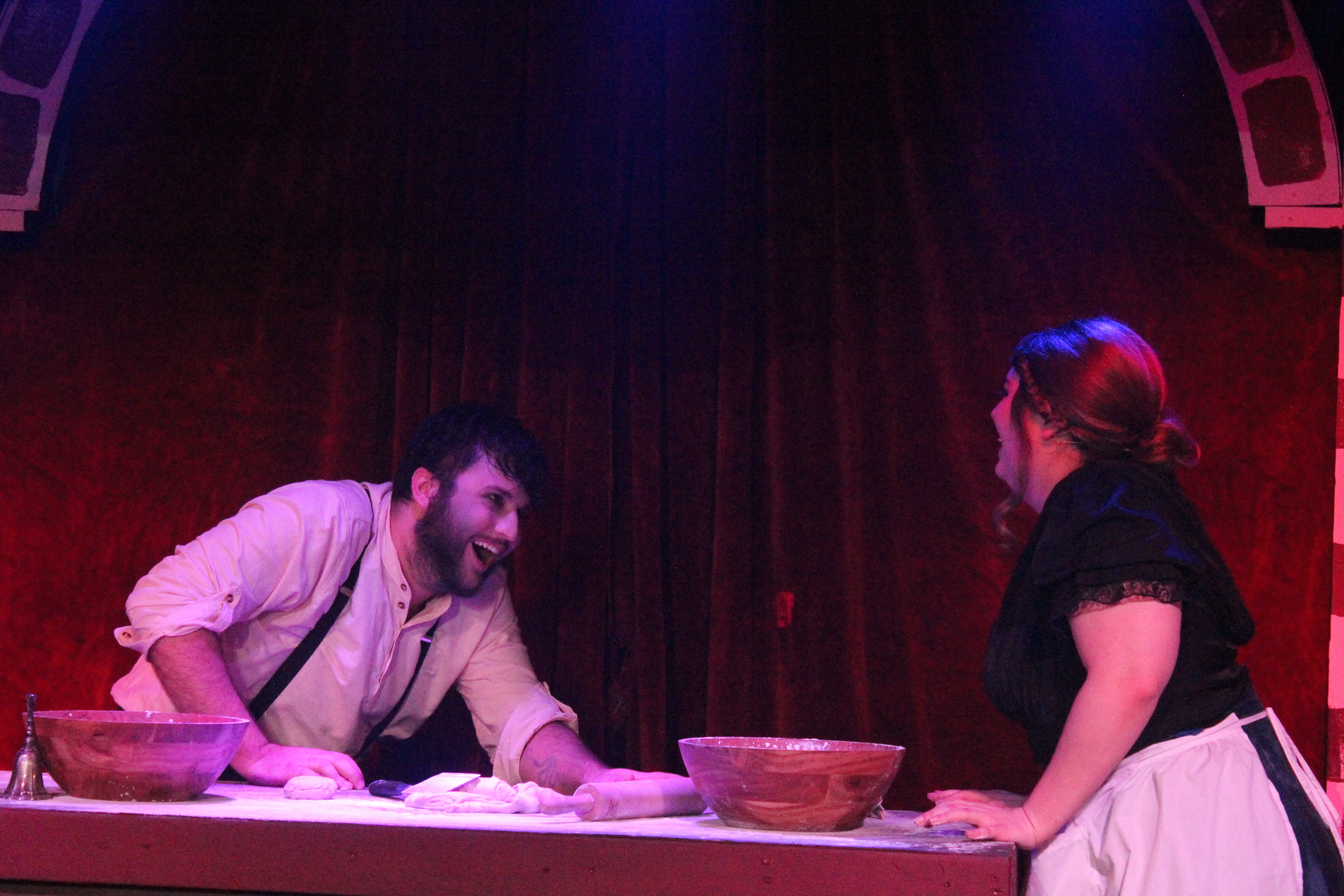 Sweeney Todd leans across a worktable toward Mrs. Lovett on a brick-and-wood set in Swoop Troupe's Sweeney Todd.