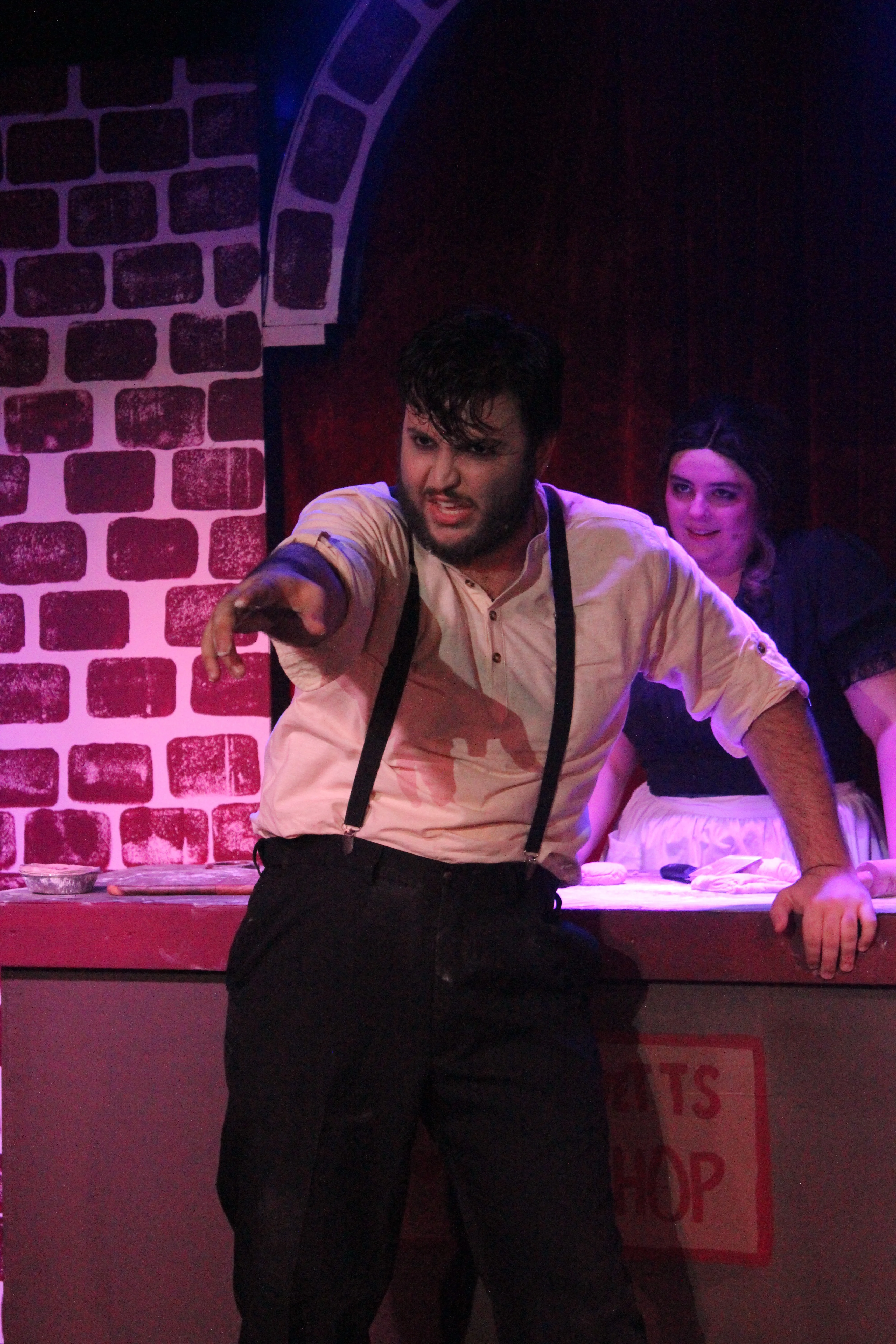 Sweeney Todd points outward from the barber-shop counter with Mrs. Lovett behind him on Swoop Troupe's brick-lined stage.